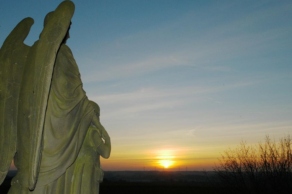 Statue eines Schutzengels beim Sonnenuntergang